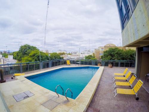 una piscina con due sedie gialle e un edificio di Alkazar Hotel a San Juan