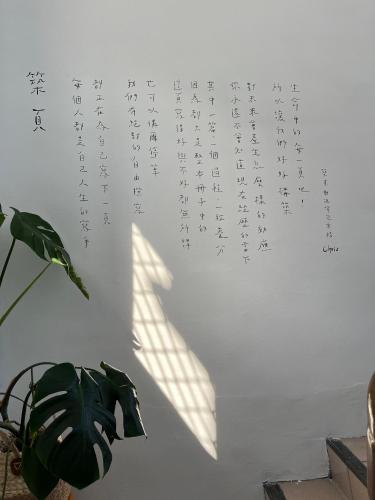 a white wall with writing on it with a plant at PageSurfingInn in Donghe