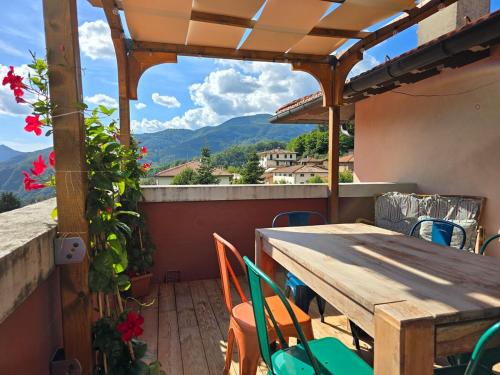 un tavolo in legno con sedie e un balcone con vista. di La terrazza sul Tetto a San Marcello Pistoiese