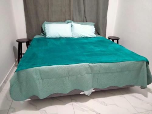 a bed with a green comforter in a room at Casa Cordelia Mangaratiba Centro in Mangaratiba