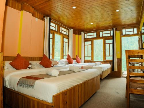 a row of beds in a room with windows at Venky's Place in Jibhi