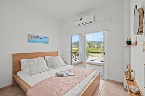 a bedroom with a bed and a balcony at Lagoon Blue Beach House by Nomads in Kato Yialia