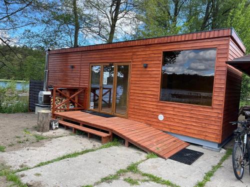 a tiny house with a large window and a bench at Domek całoroczny HAWAJE nad jeziorem Kazub in Cieciorka