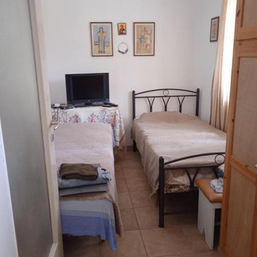 a small room with two beds and a television at Ikarian Family Cottage, Ikaria Droutsoulas in Akamatra