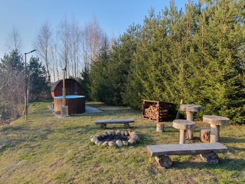 a park with two benches and a fire pit at Domek Pod Lasem in Tolejny