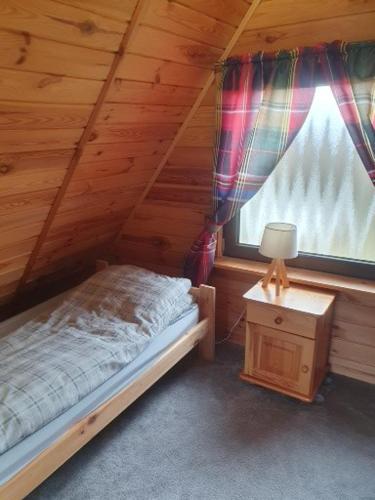 a bedroom with a bed and a window in a cabin at Domek Pod Lasem in Tolejny