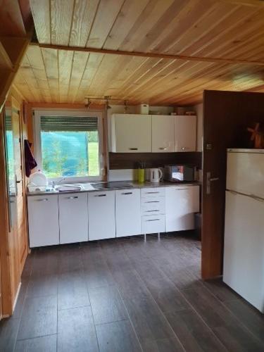 a small kitchen with white cabinets and a refrigerator at Domek Pod Lasem in Tolejny