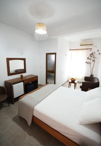 a bedroom with a large white bed and a desk at Te Rrapi Rooms in Qeparoi i Sipërm