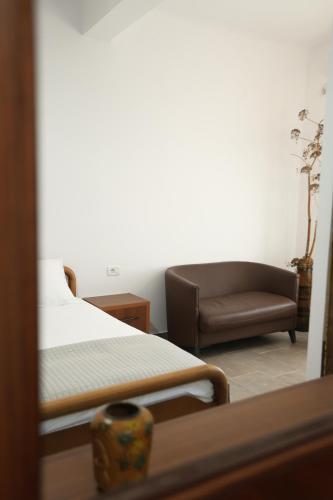 a bedroom with a couch and a bed and a chair at Te Rrapi Rooms in Qeparoi i Sipërm