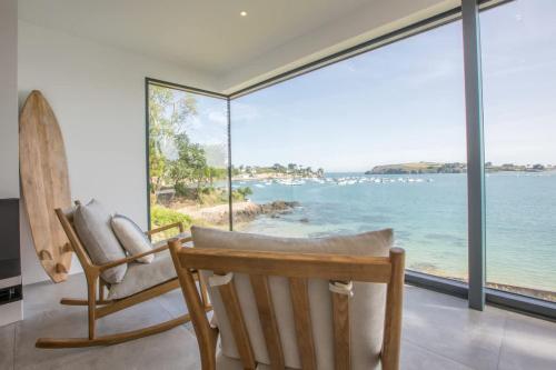 - une chambre avec deux chaises et une vue sur l'océan dans l'établissement Villa Galéo - Maison d'exception à Rotheneuf, à Saint-Coulomb