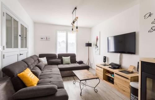 un salon avec un canapé et une télévision à écran plat dans l'établissement Le DÉRIVEUR - Maison familiale rénovée 3 chambres - Jardin et terrasse, à Saint-Lunaire