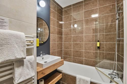a bathroom with a tub and a sink and a shower at Appart'hôtel Odalys City - Bioparc Lyon Est in Lyon