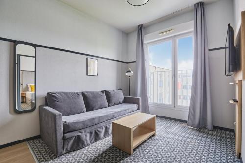 a living room with a couch and a window at Appart'hôtel Odalys City - Bioparc Lyon Est in Lyon