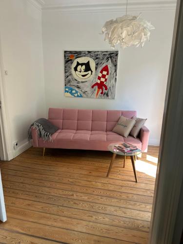 a pink couch in a living room with a painting at Apartmenthaus Hamburg Eppendorfer Weg in Hamburg