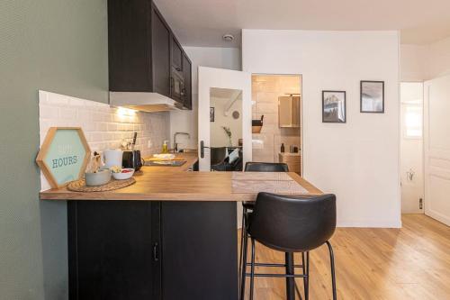 une cuisine avec un comptoir et deux tabourets de bar dans l'établissement Coquelin - Joli appartement rénové, à Rennes