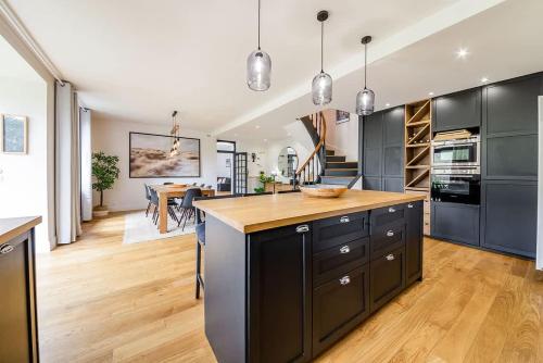 une cuisine avec des armoires noires et un plancher en bois dans l'établissement CLOS HILY - Maison d'exception à Dinard - 10 pers, à Dinard
