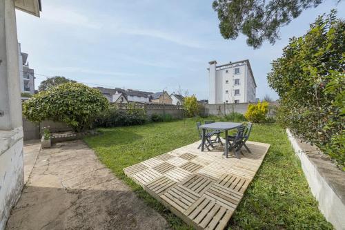 un patio avec une table et des chaises dans une cour dans l'établissement Le Green, appartement rénové, 4 chambres et jardin, à Saint-Jacques-de-la-Lande