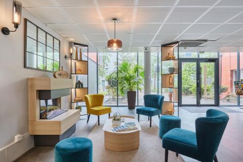 a living room with blue and yellow chairs at Appart'hôtel Odalys City - Bioparc Lyon Est in Lyon