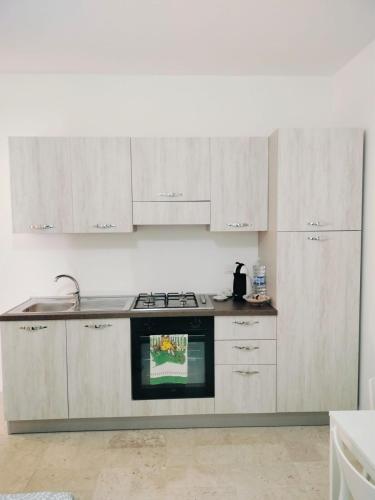 a kitchen with white cabinets and a stove top oven at Madonnina House in pieno centro in Lamezia Terme