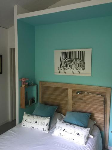 a bed with two pillows and a picture of zebras at La maison de caroline in Marcheprime