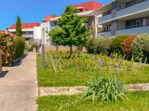 un jardin en face d'un bâtiment avec un arbre et des fleurs dans l'établissement Nouveau T3 Caudalie Piscine Proche Montpellier et Plages, à Montferrier-sur-Lez