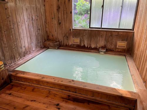 a hot tub in a wooden room with a window at 四季彩の宿やまぶき in Matsumoto