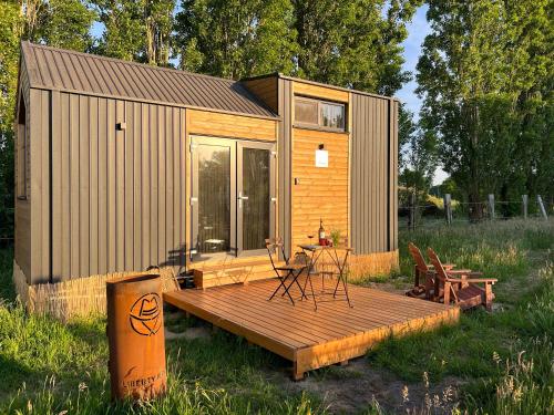 a small cabin with a deck and a table and chairs at Liberty Lodge by Tiny Away in Kalmthout