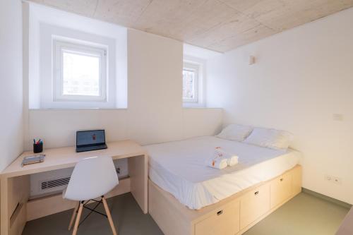 a bedroom with a bed with a desk and a laptop at StudentVille Palmeiras in Lisbon