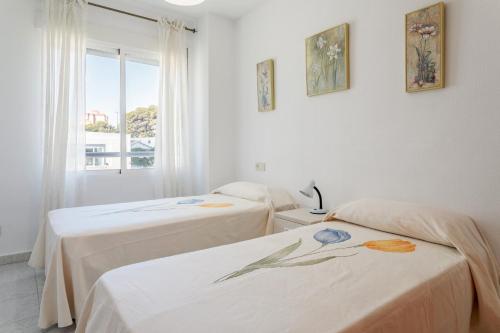 two beds in a room with a window at Morasol in El Campello