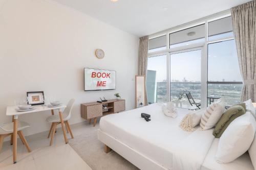 a white bedroom with a bed and a desk and a window at Majestic Studio in Damac Carson C in Dubai Marina