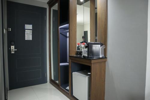 a room with a mirror and a kitchen with a refrigerator at Hotel Dafam Semarang in Semarang