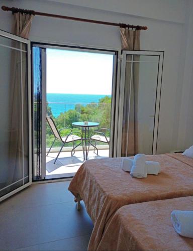 a bedroom with two beds and a balcony with a table at Rena Studios in Paleokastritsa