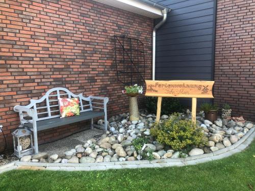 a garden with a bench and a sign in front of a building at Ferienwohnung "Fehn-Moor" 95156 in Rhauderfehn