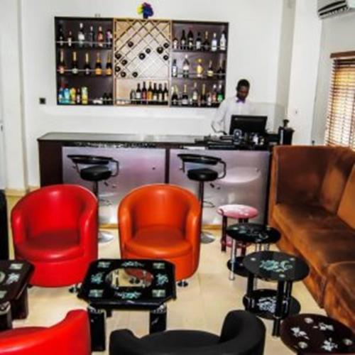 un bar con sedie rosse e un uomo dietro un bancone di Royal Jatoz Hotel and Suites a Lagos