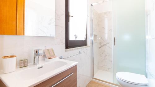 a white bathroom with a sink and a shower at Sardinianworld - Casa Mandriola in Putzu Idu
