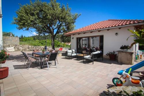 a patio with a table and chairs and a house at Apartments Biserka G in Palit