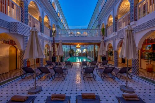 a hotel lobby with a pool and chairs and umbrellas at Palais Moulay Said & SPA in Marrakech