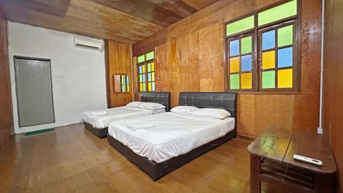 バリック・プラウにあるQuadruple Traditional Wooden GuestHouseのステンドグラスの窓が備わる客室内のベッド2台