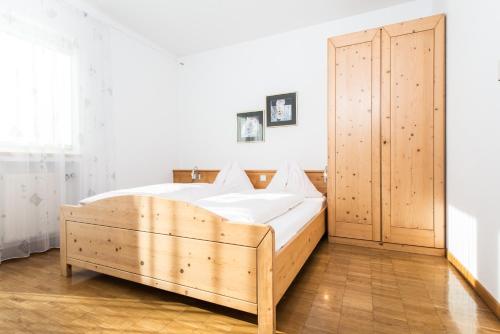 a bedroom with a wooden bed and a wooden closet at Residence Auriga in Campo Tures