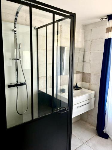 a shower with a glass door in a bathroom at Gîte Molière in Sallèles-dʼAude