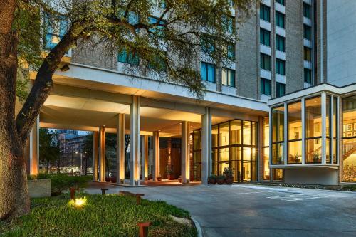 a building with large glass windows and a tree at The Highland Dallas, Curio Collection by Hilton in Dallas