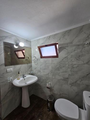 a bathroom with a sink and a toilet and a window at Bliss Apartment in Qeparoi i Sipërm