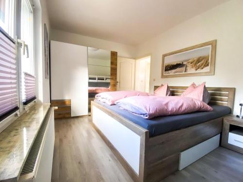 une chambre avec un lit avec des oreillers roses dessus dans l'établissement Landhaus Kreitlow, à Ribnitz-Damgarten