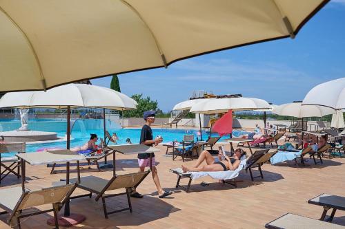 a group of people sitting in chairs by a pool at Salvapiano Holiday Ranch in Riotorto