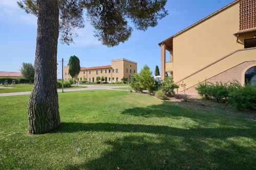 a tree in a field next to a building at Salvapiano Holiday Ranch in Riotorto