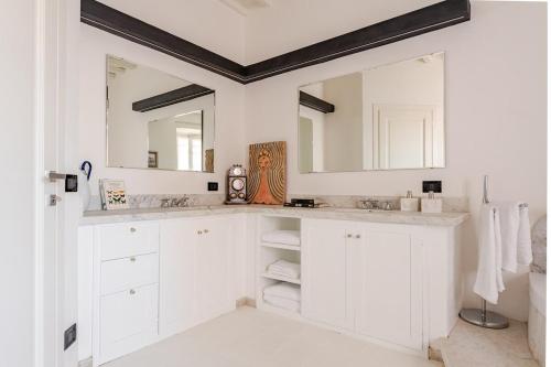 a white bathroom with two sinks and two mirrors at Cosimo Charme in Chianti in Barberino di Val dʼElsa