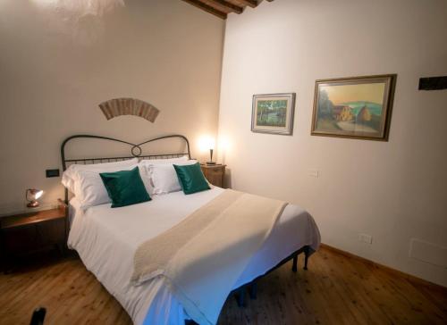 a bedroom with a large white bed with green pillows at Cosimo Charme in Chianti in Barberino di Val dʼElsa