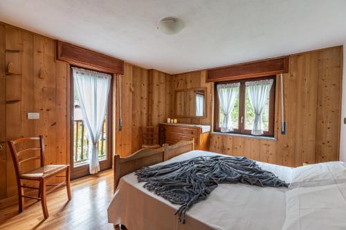 a bedroom with a bed and wooden walls and windows at L'Atelier du Temps - Casa Sonveulla in Cogne