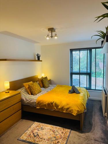 a bedroom with a bed with yellow sheets and a window at Fly Hi-Town Centre Apartment in Ifield