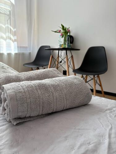 a blanket on a bed in a room with chairs at Słoneczny Zakątek in Suwałki
